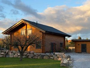 Blockbohlenhaus mit Garage: Natürliches Holzdesign, hochwertige Doppelblockbohlen-Konstruktion, überdachte Terrasse und praktischer Geräteraum. Perfekt für gemütliches Wohnen in ländlicher Umgebung.